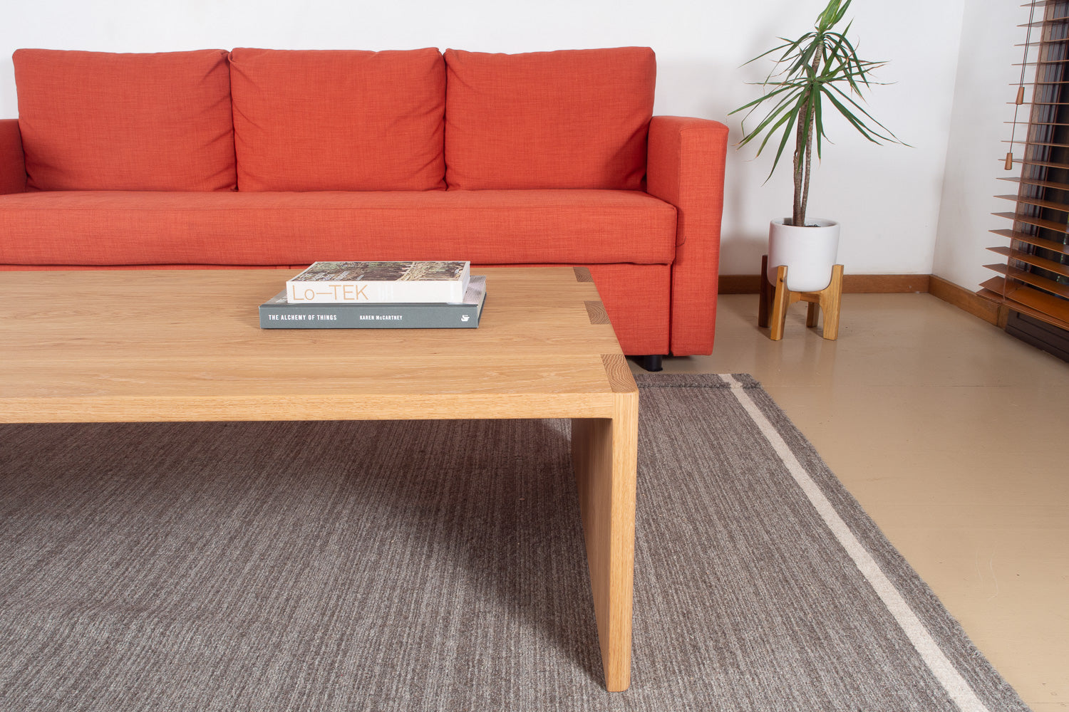 The Mesa Coffee Table in White Oak with two books in front of a sofa and on a rug. Designed and made by Hey, Porter.