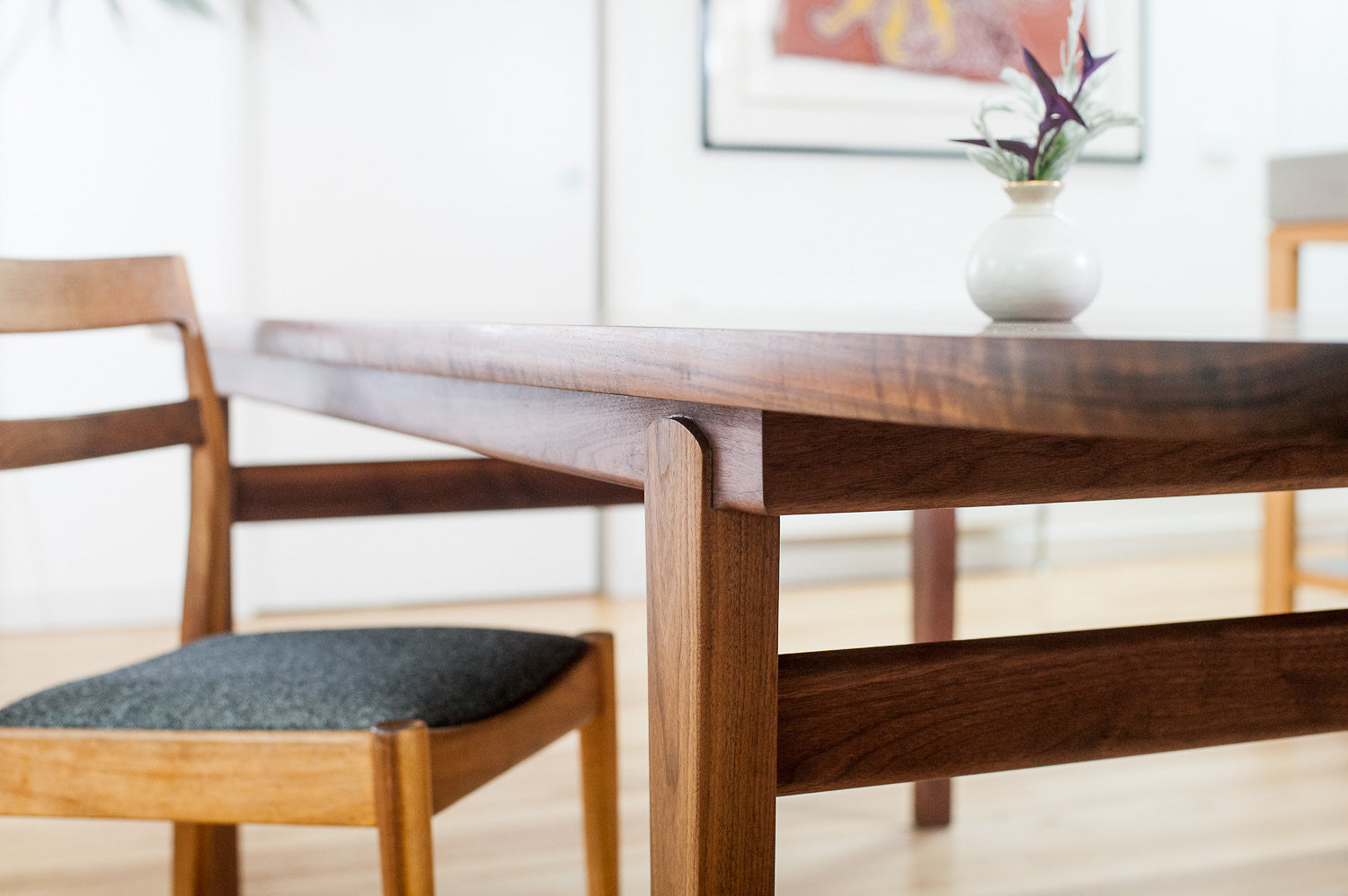 Wesley Dining Table in Walnut - detailed view of leg joinery with dining chair. Designed and made by Hey, Porter.